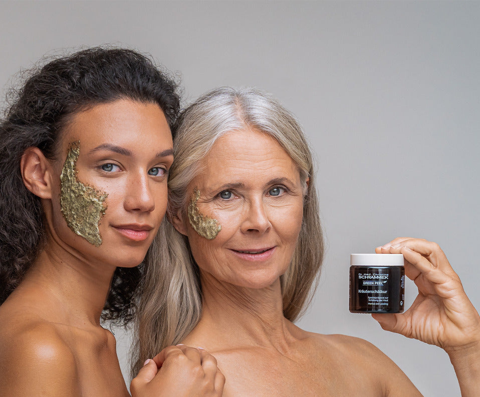 Two women of different ages with a green peel on their cheeks. One holds a jar of Dr. Schrammek Green Peel.